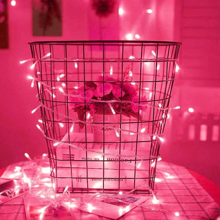 VibeCore 10M Colorful Traditional String Lights in Pink on Table, creating a soft, vibrant glow that adds a touch of warmth and playfulness to your space. Perfect for decorating your table and creating a cozy atmosphere.