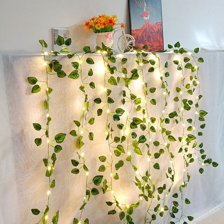 Leaf vine string lights draped over mantle, cozy decor.