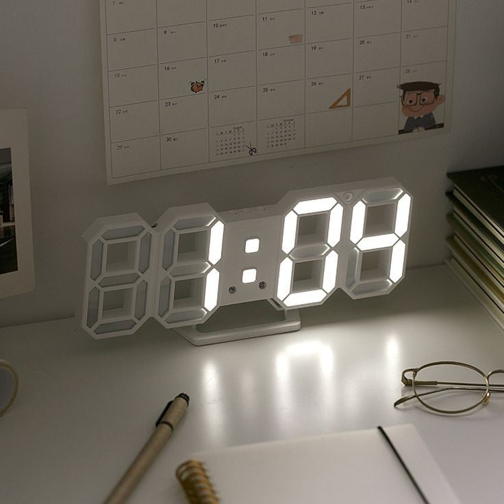 VibeCore 3D LED Digital Alarm Clock in white with white light, displayed on desk. Featuring bold, illuminated 3D LED digits for easy readability, this modern alarm clock offers additional features like a thermometer, perpetual calendar, and moon phase display. Its sleek rectangular design adds a contemporary touch to any room, making it a perfect addition to both bedrooms and offices.
