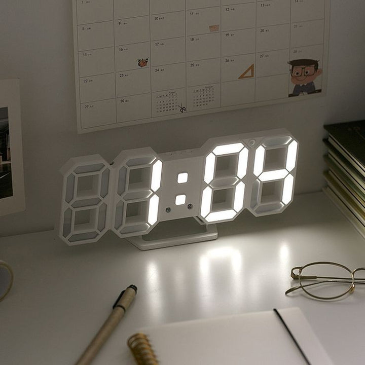 VibeCore 3D LED Digital Alarm Clock in white with white light, displayed on desk. Featuring bold, illuminated 3D LED digits for easy readability, this modern alarm clock offers additional features like a thermometer, perpetual calendar, and moon phase display. Its sleek rectangular design adds a contemporary touch to any room, making it a perfect addition to both bedrooms and offices.