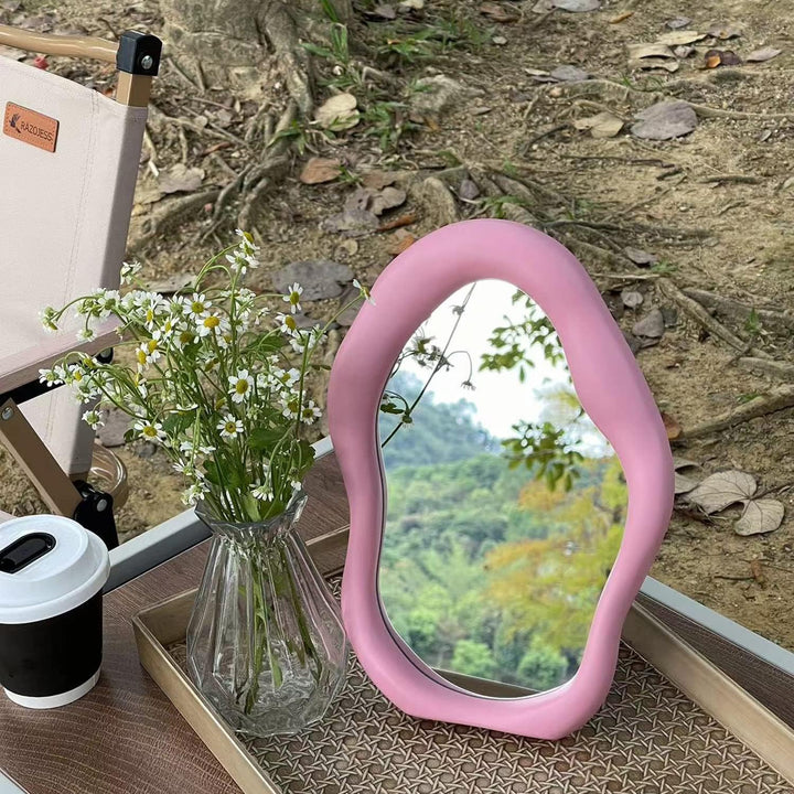 VibeCore Abstract Blob Makeup Mirror in Light Pink, beautifully placed on an outdoor table, adding a pop of color and modern aesthetic to your outdoor space.