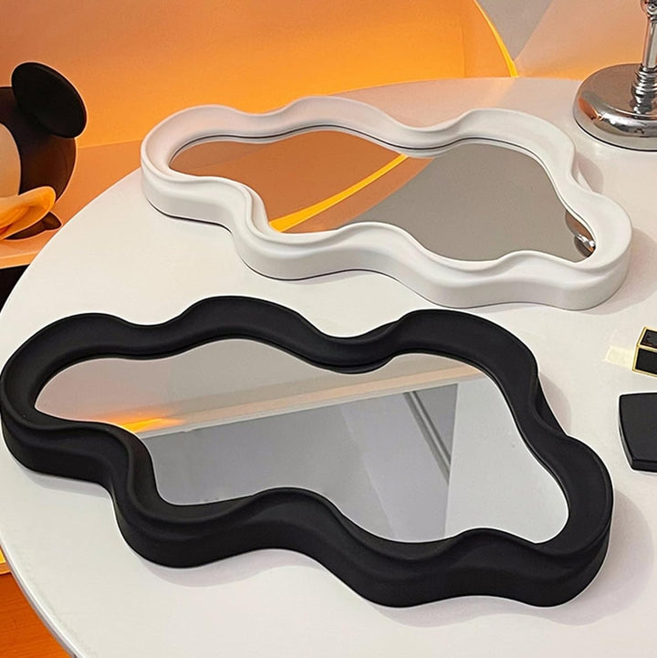 VibeCore Abstract Curve Wall Mirror Black and White Ripple On Table: A modern black and white ripple-patterned wall mirror placed on a table, showcasing its unique curve and minimalist design, perfect for enhancing any room.