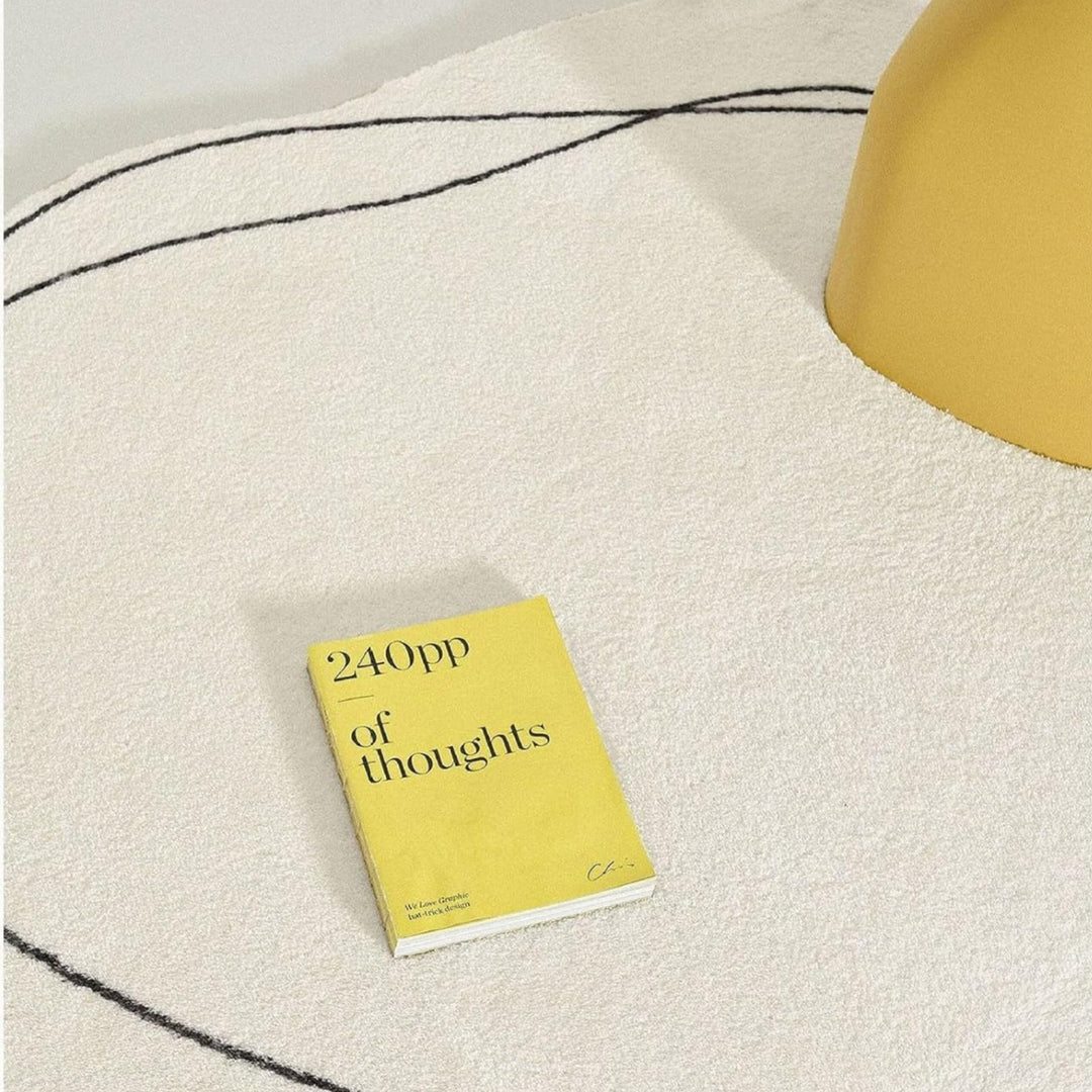 VibeCore Abstract Squiggle Area Rug close-up with a book resting on it. The rug's playful squiggle design is showcased, with the soft imitation cashmere texture adding elegance to the cozy and artistic setup.