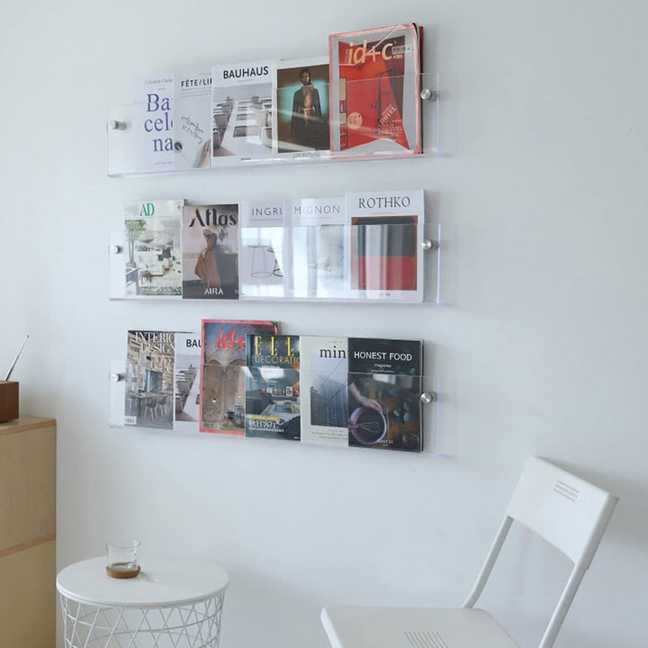 VibeCore Acrylic Wall Mounted Floating Magazine Shelf in transparent, showcasing three products stacked on top of one another with magazines neatly organized inside.