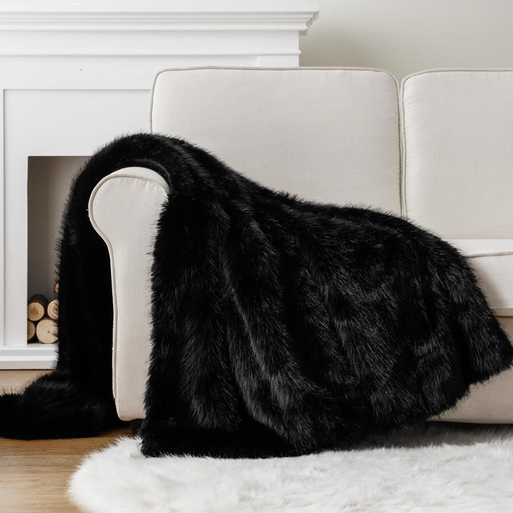 Black Arctic Dream Faux Fur Throw Blanket draped over a couch in a living room, adding a luxurious, European-inspired touch. Soft and plush, perfect for enhancing the warmth and elegance of your space.