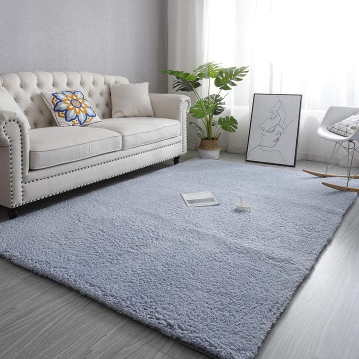 VibeCore Arctic Faux Cashmere Area Rug in gray placed in a living room, featuring a soft faux cashmere texture with non-slip backing. Adds warmth and luxury to any space, perfect for enhancing comfort and style. Easy to clean and available in 11 color options.