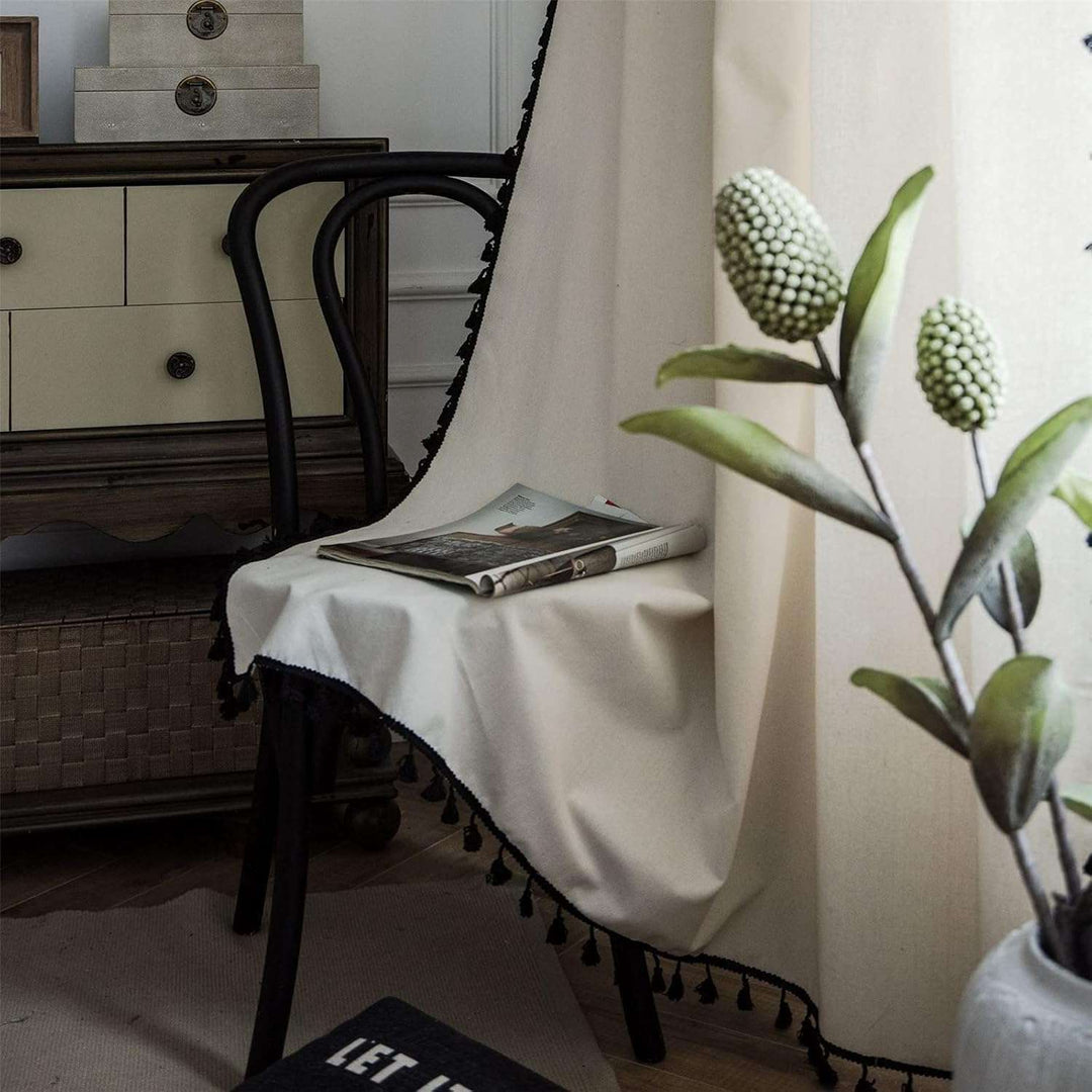 Beige tassel linen curtain draped on a chair, showcasing soft fabric and tassel accents.