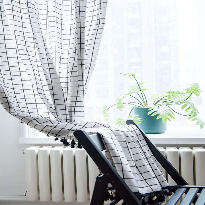 VibeCore Black & White Grid Tassel Linen Curtain in living room, featuring a bold grid pattern and playful tassels, light-filtering design crafted from a soft cotton-linen blend, perfect for adding contemporary bohemian charm to your space.