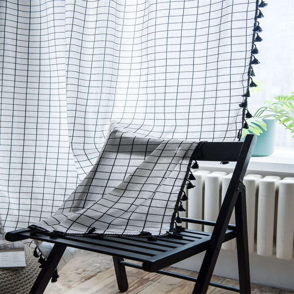 VibeCore Black & White Grid Tassel Linen Curtain on chair, showcasing a bold grid pattern with playful tassels, crafted from a soft cotton-linen blend, perfect for adding contemporary bohemian charm to your space.