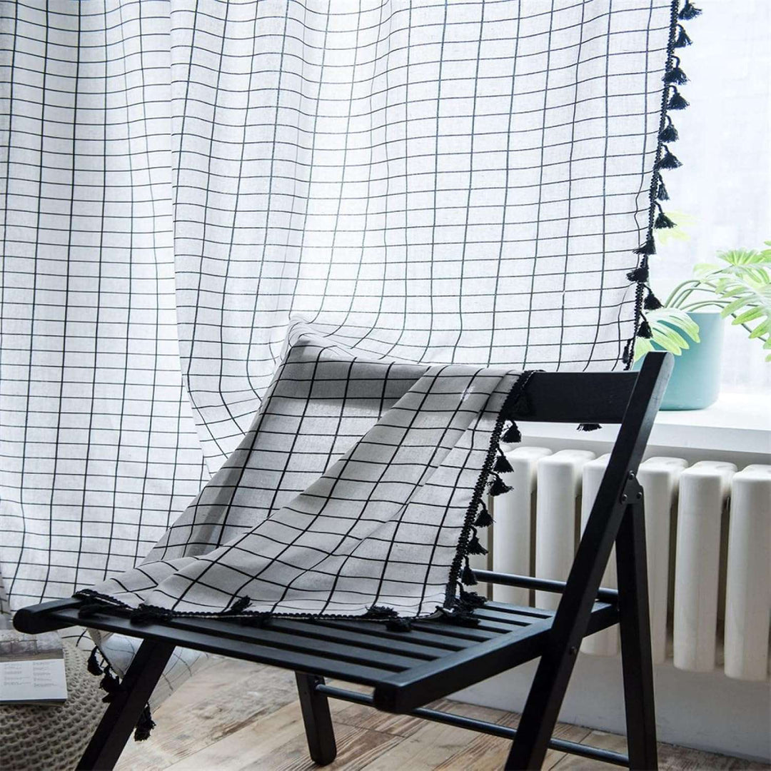 VibeCore Black & White Grid Tassel Linen Curtain on chair, showcasing a bold grid pattern with playful tassels, crafted from a soft cotton-linen blend, perfect for adding contemporary bohemian charm to your space.