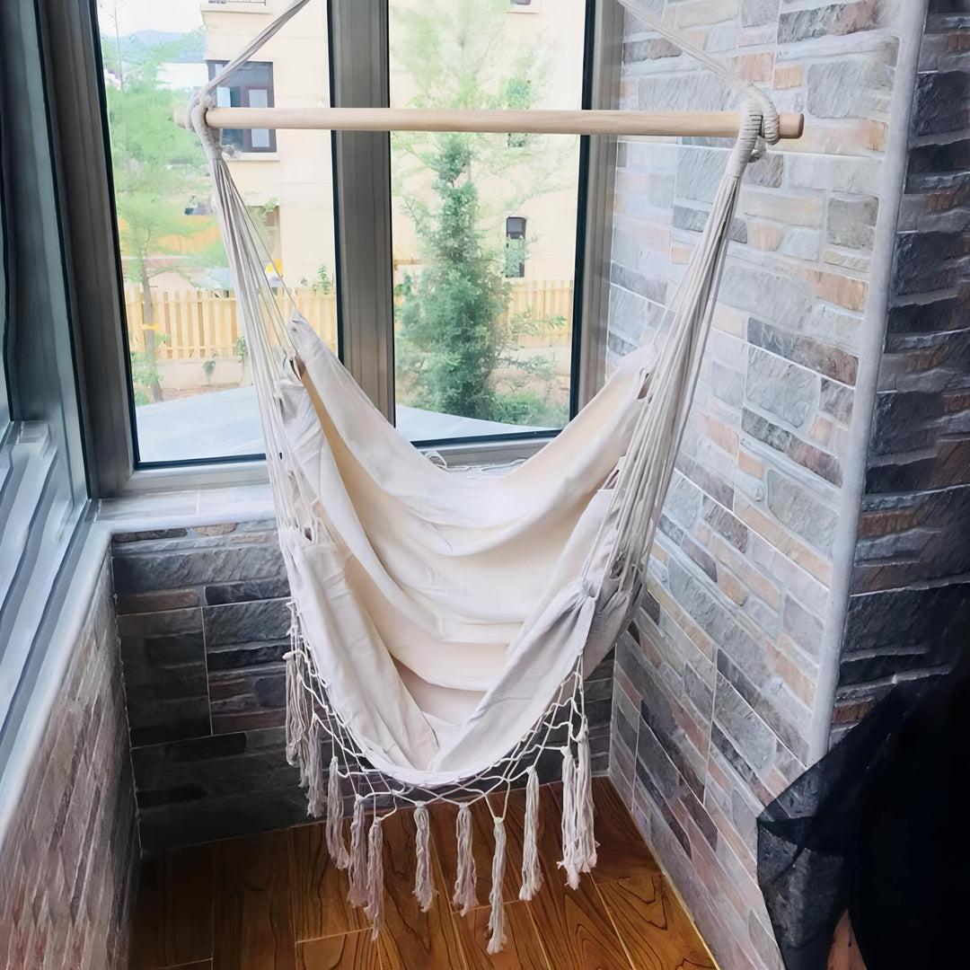 Aesthetic Bohemia style hanging hammock chair hanging by a window made of high-quality cotton thread perfect for adding a cozy, bohemian touch to your space while providing durable comfort for lounging or reading.