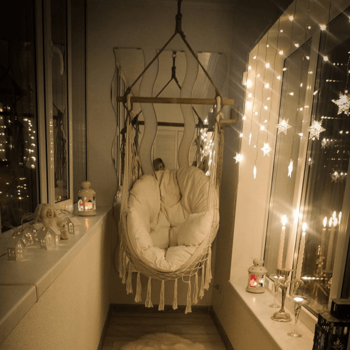 Aesthetic Bohemia style hanging hammock chair on a balcony made of high-quality cotton thread perfect for adding a cozy, bohemian touch to your outdoor space while providing durable comfort for lounging or reading.