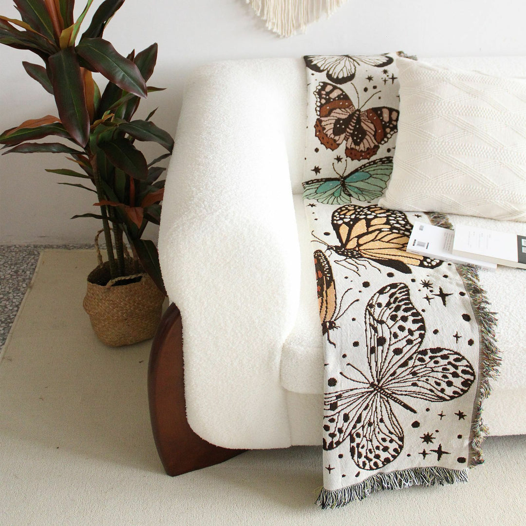 VibeCore Butterflies Woven Blanket draped on couch, folded, showcasing vibrant butterfly design and soft 100% combed cotton texture.