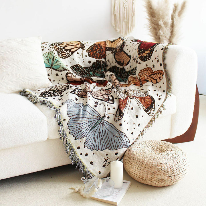 VibeCore Butterflies Woven Blanket draped over couch, showcasing delicate butterfly design and soft 100% combed cotton texture.