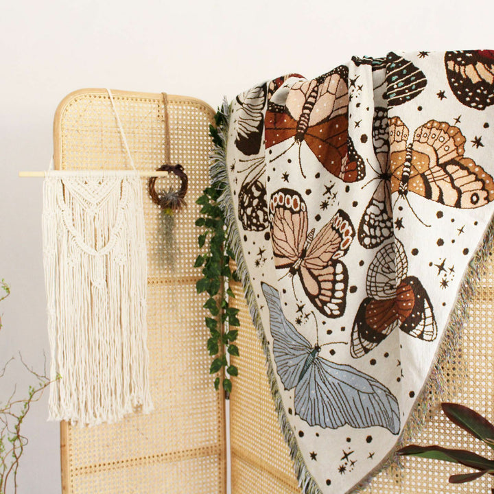 VibeCore Butterflies Woven Blanket draped over couch, featuring vibrant butterfly design and soft 100% combed cotton texture.