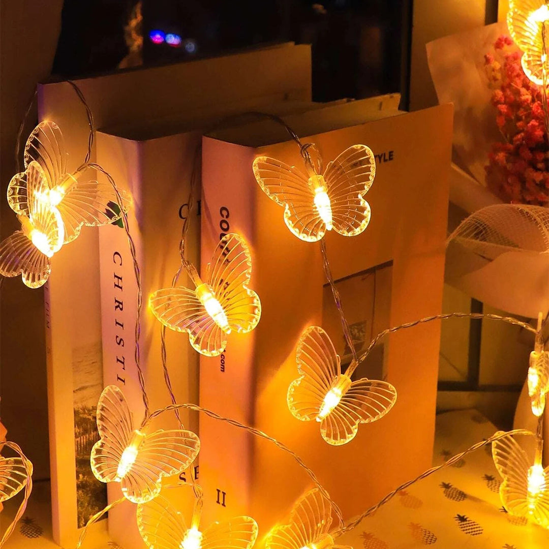 VibeCore Butterfly String Lights draped over books, creating a cozy, whimsical atmosphere with delicate butterfly designs and warm white glow.