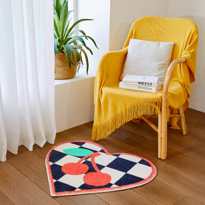 VibeCore Cherry Chessboard Accent Rug in front of a chair, featuring playful cherry designs and classic chessboard patterns. Soft, fluffy texture with a non-slip backing, perfect for adding comfort and style to any room. Durable and easy to clean.