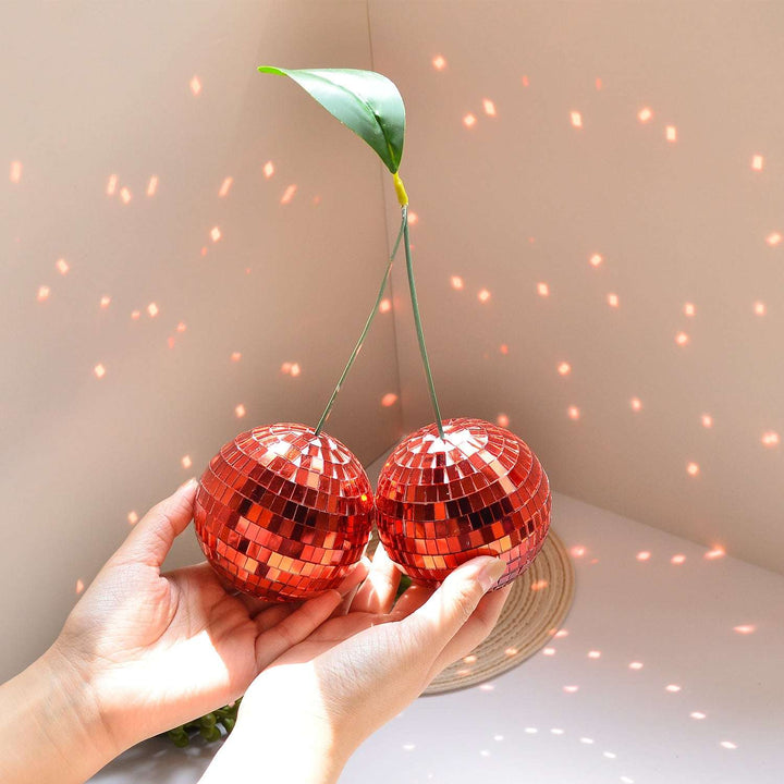 VibeCore Cherry Disco Ball Red being held up, displaying its vibrant mosaic finish and geometric shape, radiating playful charm and adding a fun, colorful touch to any space.
