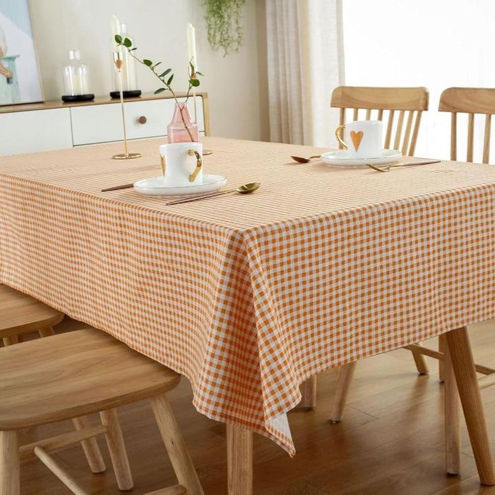 VibeCore Classic Picnic Plaid Tablecloth orange on table, showcasing a vibrant plaid design with waterproof, fade-resistant fabric, perfect for stylish table settings at any gathering.