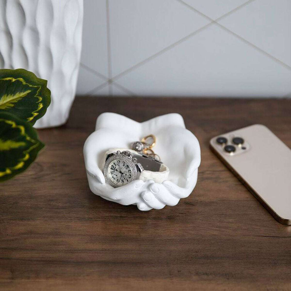 The VibeCore Closed Hands Display Tray placed on a table, showcasing its sleek white design and unique closed hands shape, perfect for organizing jewelry or small treasures.