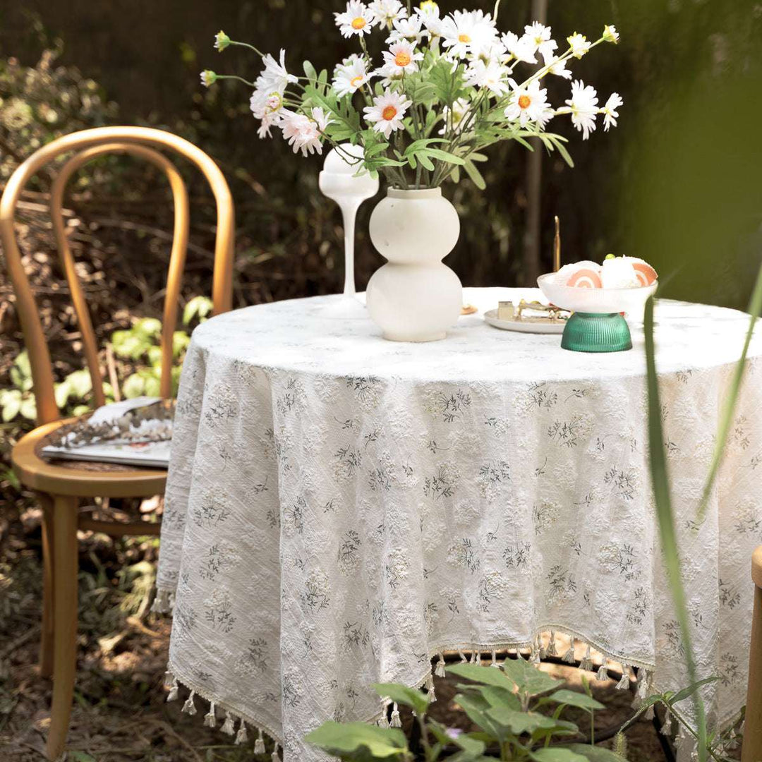 VibeCore Clove Flower Tassel Linen Tablecloth featuring delicate floral patterns and charming tassel edges, draped elegantly over a table, adding a stylish and sophisticated touch to the dining space.
