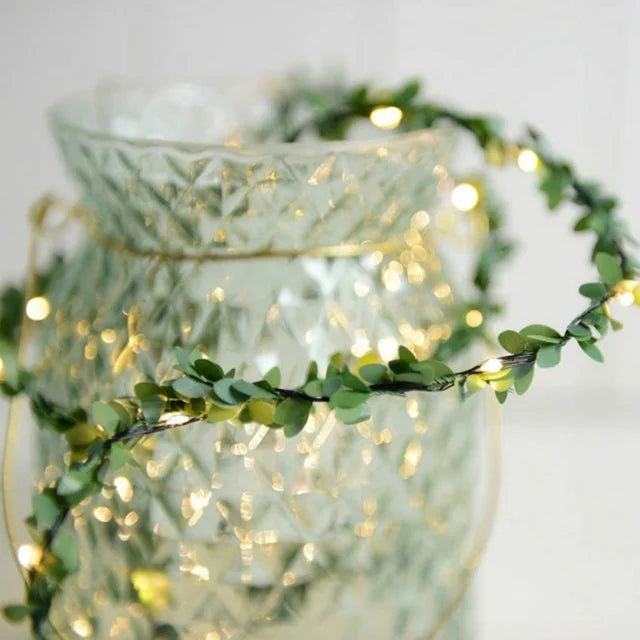 Close-up detail of VibeCore copper leaf garland string lights, highlighting the warm white LEDs nestled within the lush, artificial leaves for a cozy, vibrant glow.