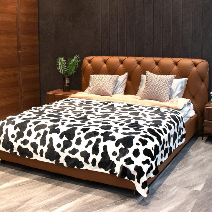 Black cow print throw blanket on a bed, offering a bold, trendy design and cozy comfort. Perfect for adding a fun and stylish touch to your bedroom.