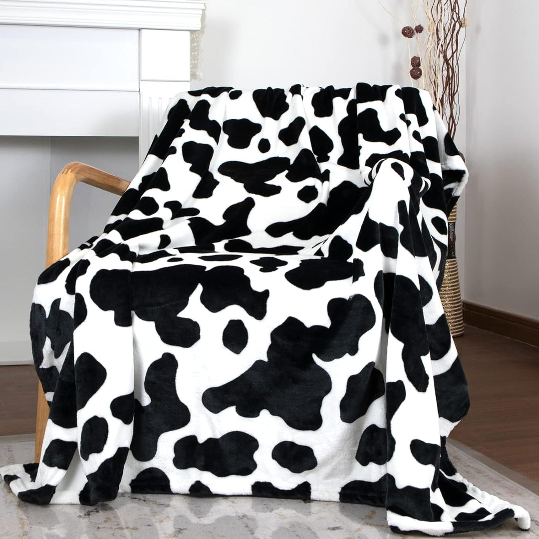 Black cow print throw blanket on a chair, bringing a bold, trendy accent to your space. Soft and cozy, perfect for adding personality and comfort to any room.