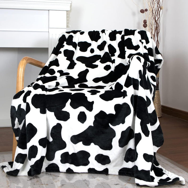 Black cow print throw blanket on a chair, bringing a bold, trendy accent to your space. Soft and cozy, perfect for adding personality and comfort to any room.