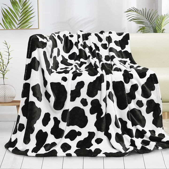 Black cow print throw blanket draped over a sofa, adding a bold, trendy touch to your space. Soft, cozy, and perfect for enhancing your living room with personality and style.