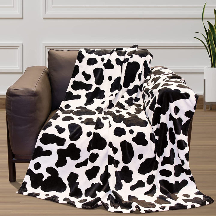 Black and white cow print throw blanket on a sofa chair, adding a bold and trendy accent to your space. Soft, cozy, and perfect for a chic, playful touch in any room.