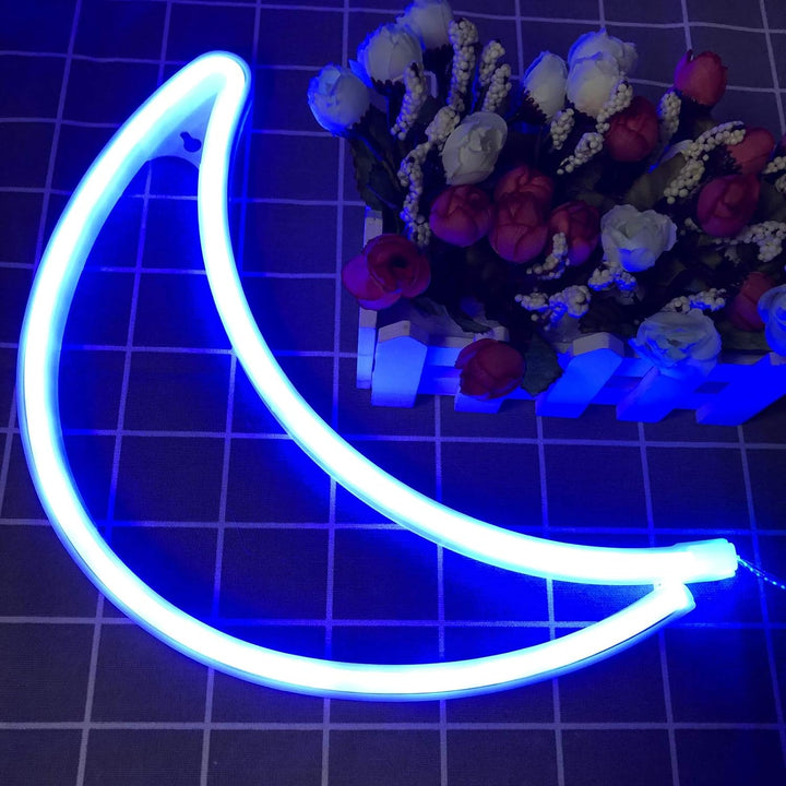 VibeCore Crescent Moon Neon Light Blue on table, softly glowing with a calming blue light, adding a serene and mystical ambiance to the space.