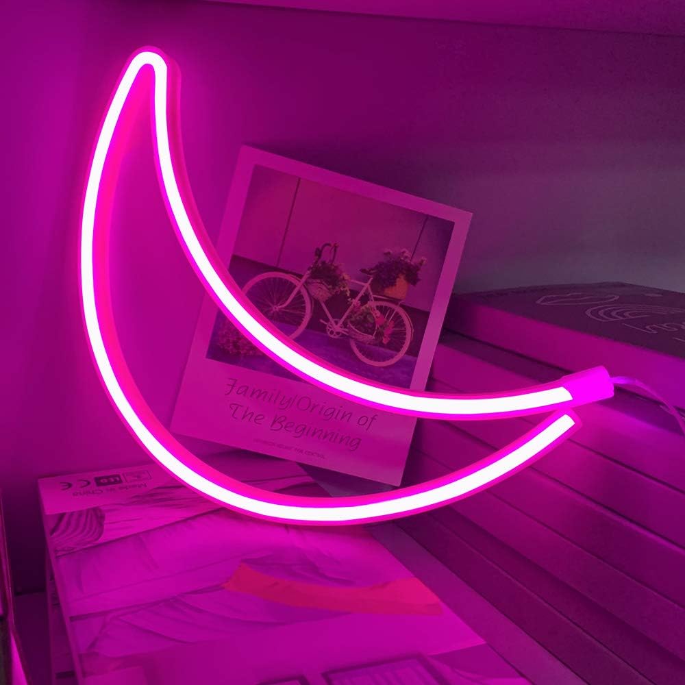 VibeCore Crescent Moon Neon Light Pink, placed on a table, casting a soft pink glow that adds a dreamy and calming ambiance to the space.