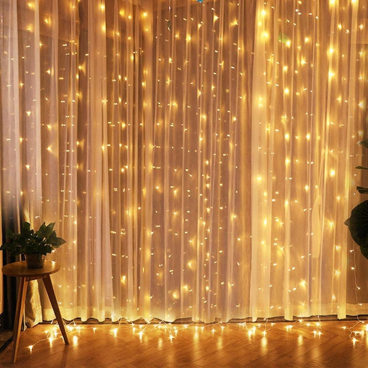 Warm white curtain string lights hanging, adding vibrant ambiance to the room. USB-powered, remote-controlled, with 8 lighting modes for customizable decor.