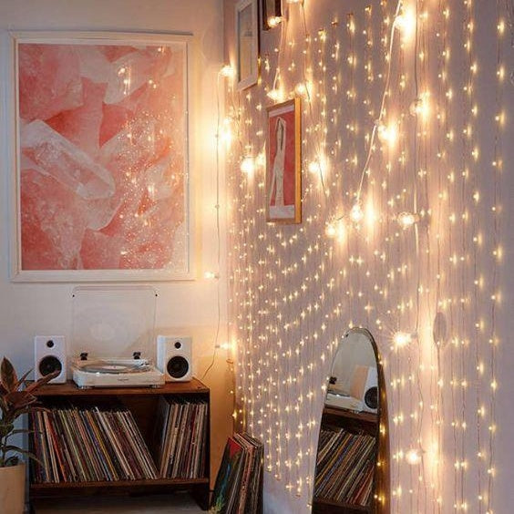 Warm white curtain string lights hanging on living room wall, adding a cozy and vibrant touch.