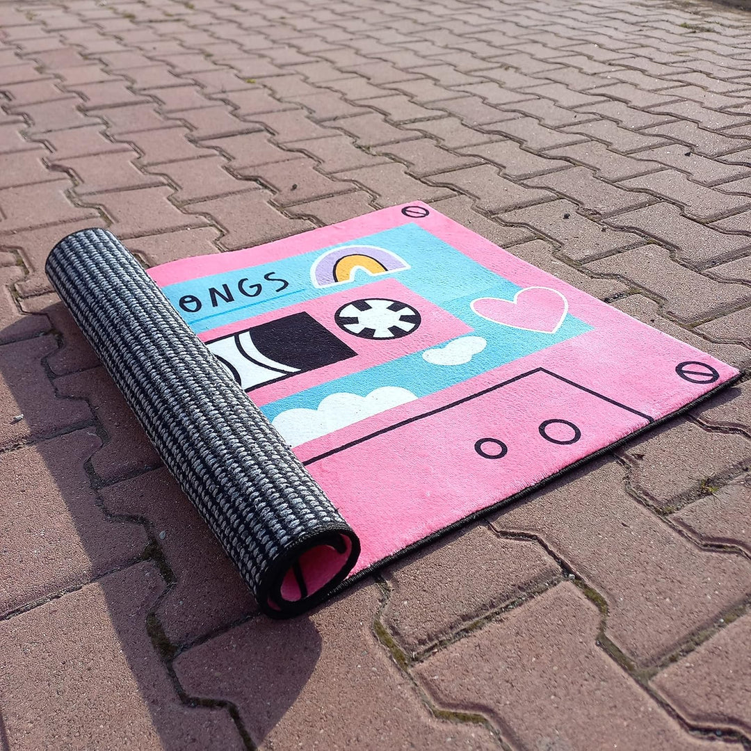 VibeCore Cute Cassette Accent Rug in pink, neatly rolled up to showcase its compact size and soft, plush material. The rolled-up rug reveals its vibrant design and high-quality texture.