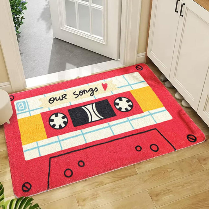 VibeCore Cute Cassette Accent Rug in red, placed in a doorway, featuring a bold retro cassette tape design. The soft texture and non-slip backing make it both stylish and practical for high-traffic areas.