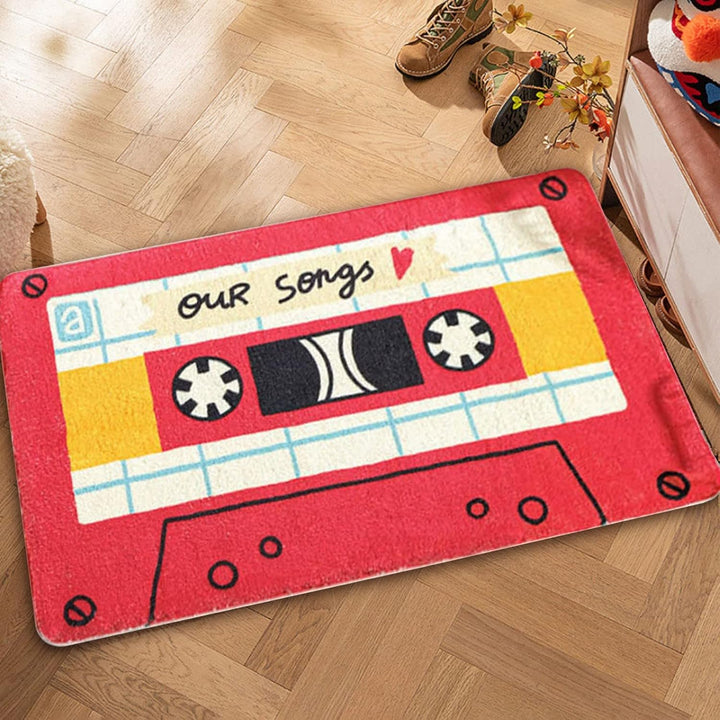 VibeCore Cute Cassette Accent Rug in red, placed on the floor, showcasing a playful retro cassette tape design. Its plush texture and non-slip backing add comfort and safety to any space.