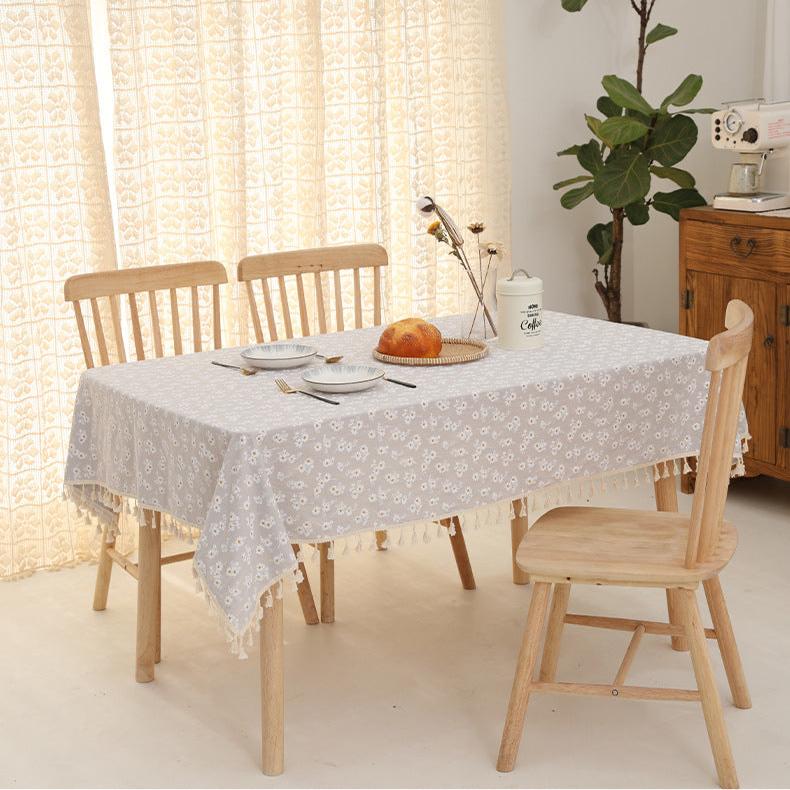VibeCore Daisy Embroidered Linen Tablecloth in gray, laid on a square table, showcasing delicate daisy embroidery and tassel details for a stylish and charming table setting.