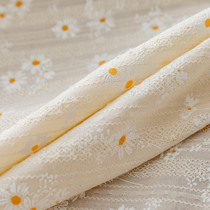 VibeCore Daisy Embroidered Linen Tablecloth in white, close-up view highlighting the delicate daisy embroidery and tassel accents, showcasing its soft, high-quality linen texture.