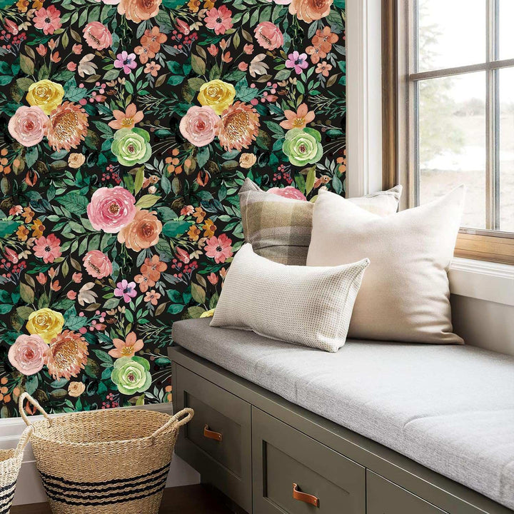 A view of the dark watercolor floral self-adhesive wallpaper on the wall behind a cozy window bench, adding a bold, artistic touch to the space with its vibrant floral design on a dark background.