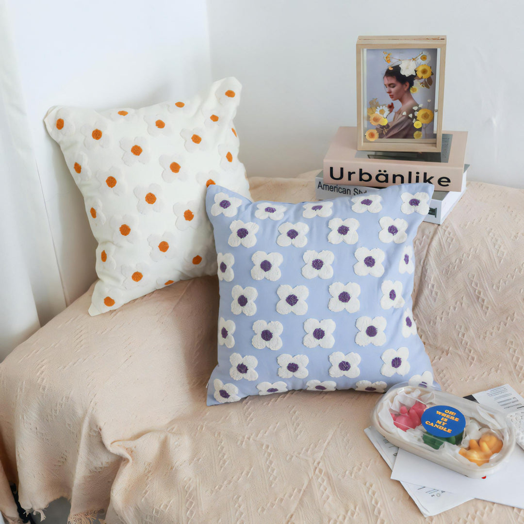 White and lavender square throw pillow covers with hand-stitched embroidered daisies, placed on a couch, adding a fresh and floral touch to the decor. Made from soft, breathable cotton with a concealed zipper closure for a polished look.