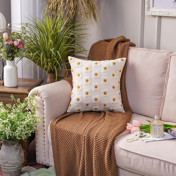 White square throw pillow covers with hand-stitched embroidered daisies, placed on a couch. The soft, breathable cotton covers add a fresh and floral charm to the space, featuring a concealed zipper for a polished and functional design.