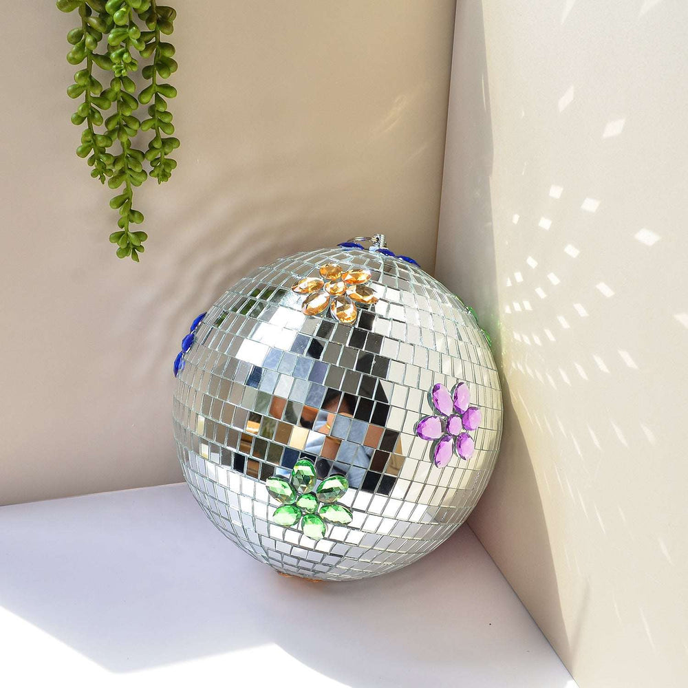 VibeCore Floral Hanging Disco Ball against a wall, showcasing its reflective surface and intricate floral patterns on a silver inlay.