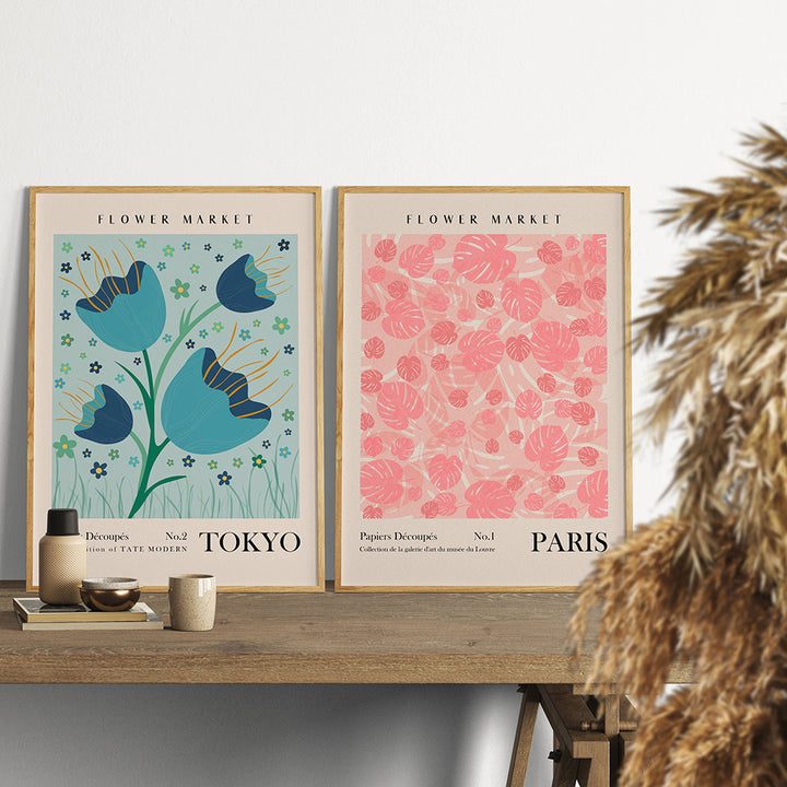 "VibeCore Flower Market Cities Canvas Posters" featuring framed prints of vibrant flower markets from Tokyo and Paris. The Tokyo print showcases lush blooms amidst the city's modern landscape, while the Paris print captures the elegance of the city's charming flower stalls, offering a worldly, floral touch to your home decor.