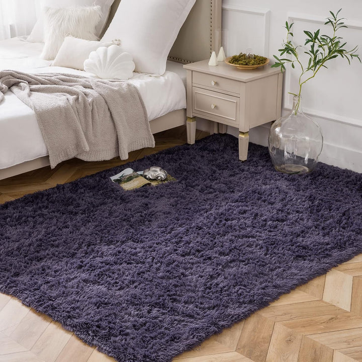 VibeCore Fluffy Area Rug in Purple and Gray placed beside a bed, adding a cozy and stylish accent to the room with its soft texture and modern color combination.