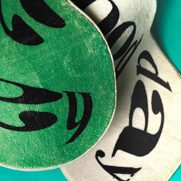 VibeCore Have A Good Day Trippy Accent Rug close-up showing both colors, green and white, with the dynamic, abstract font design. This vibrant rug features a bold text message with a groovy font shape, creating a playful and energetic vibe. The plush texture adds comfort while the striking design makes it a statement piece for your room. Perfect for those looking to add a quirky, positive touch to their space.