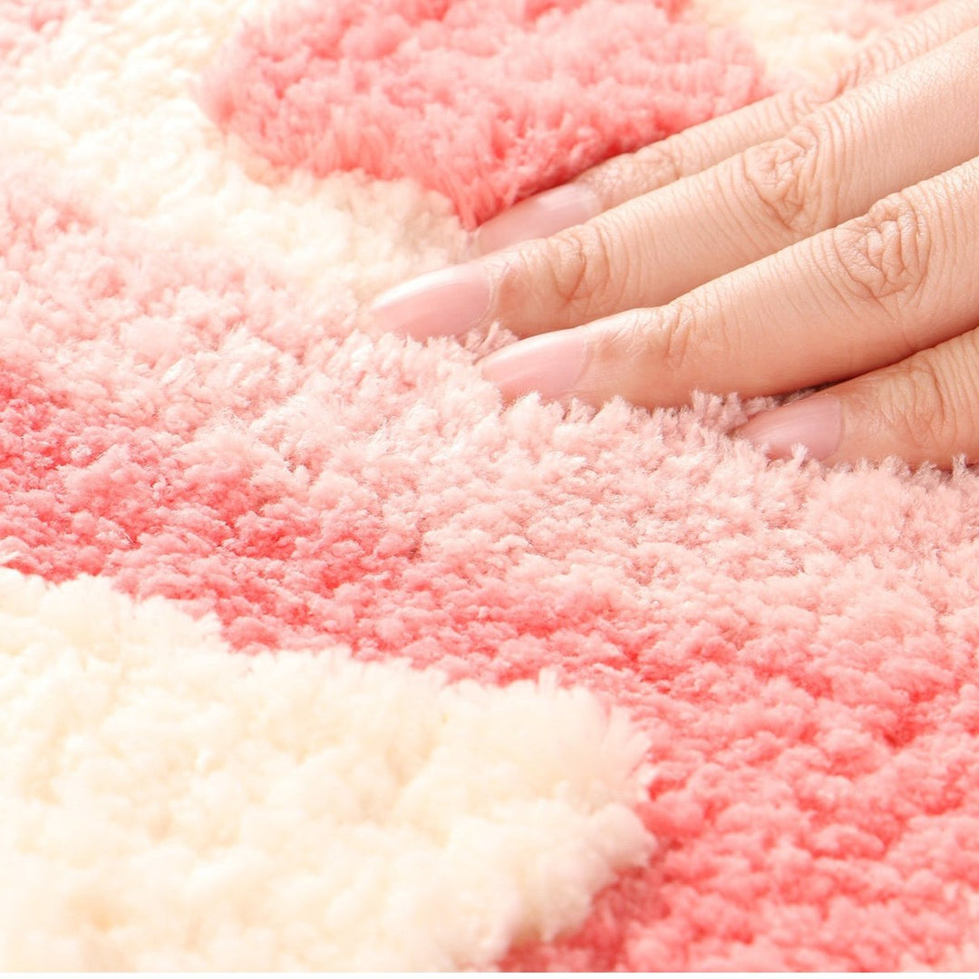 Aesthetic close-up of the material of the "Hearts Multiply Accent Rug," highlighting its soft, plush texture. The close-up showcases the vibrant pink color and quality of the fabric, emphasizing the comfort and cozy feel, along with the durable non-slip backing for added stability.