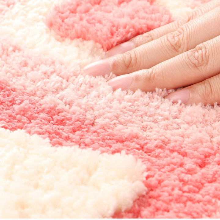 Aesthetic close-up of the material of the "Hearts Multiply Accent Rug," highlighting its soft, plush texture. The close-up showcases the vibrant pink color and quality of the fabric, emphasizing the comfort and cozy feel, along with the durable non-slip backing for added stability.