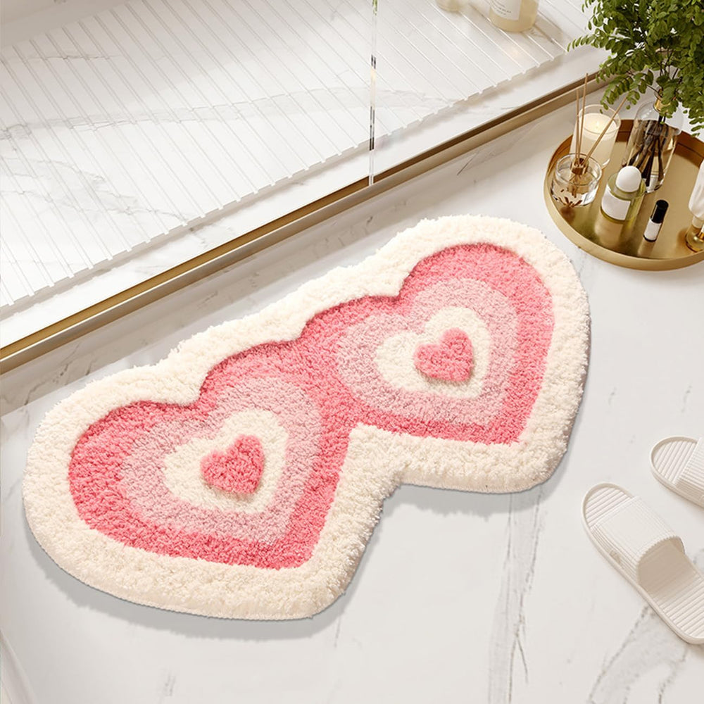 Aesthetic "Hearts Multiply Accent Rug" in small size, displayed as a bath mat. Featuring a playful pattern of multiplying hearts, this cute pink rug adds a sweet, cozy touch to your bathroom, with a soft, plush texture and non-slip backing for comfort and safety.